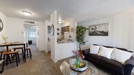 This well-organized single-floor unit offers a practical and functional layout across three distinct areas. The combined kitchen and living room serves as the heart of the space, featuring a carpeted living area with a sliding glass door fitted with vertical blinds that allows natural light to filter in. The kitchen is positioned adjacent to the living space, separated by a partial dividing wall that creates an open-pass-through feel. The kitchen is equipped with a full-size refrigerator, an electric range with overhead ventilation, a dishwasher, a single-basin sink, and ample upper and lower cabinetry finished in a warm brown tone. Wood-look flooring in the kitchen adds a clean contrast to the carpeted living zone. A textured ceiling runs throughout the unit, lending a classic residential character. The bathroom features wood-look flooring, a full-size soaking tub with a shower and curtain rod, a toilet, and a vanity with an integrated sink and countertop. A closet provides dedicated storage space to keep the unit organized. The overall layout is efficient and thoughtfully arranged, making excellent use of the available footprint while maintaining a comfortable and livable atmosphere.