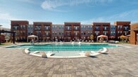 This four-story building showcases a classic brick exterior with a contemporary edge, featuring large windows, private balconies, and a warm, urban aesthetic that extends across each level. The facade combines rich red brick with neutral-toned panels, creating a structured yet inviting appearance. The standout feature of this property is its generously sized outdoor amenity courtyard, which serves as the centerpiece of the community.

The pool area includes a full-length lap pool with clearly marked lanes, ideal for fitness-oriented residents, as well as a separate wading or leisure pool with built-in submerged lounge chairs for relaxed sunbathing. The surrounding deck is finished with elegant paver stonework and is lined with chaise lounges and umbrella-shaded seating. Cabana structures with curtained canopies provide additional shade and privacy throughout the space.

A dedicated covered outdoor pavilion anchors one end of the courtyard, featuring ceiling fans, an outdoor entertainment setup, and an adjacent lounge area with modular seating. Landscaping with young trees and greenery softens the hardscape, while classic-style lamp posts add refined detail. The overall atmosphere is resort-inspired, blending active and leisure-focused amenities within a well-appointed outdoor setting.