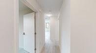 Located at 1698 University Ave in Berkeley, CA, this efficiently designed 4-bedroom, 1-bathroom unit offers a clean, modern aesthetic throughout its single floor. Light wood-style flooring runs continuously across all rooms, complementing the crisp white walls and creating a bright, cohesive interior.

The living room features an open layout adjacent to a kitchen with white cabinetry and a pass-through counter, making the shared space feel connected and functional. A central hallway connects the living areas to the four bedrooms, each finished with the same light flooring and neutral tones. The bedrooms are outfitted with black-framed windows that frame views of the surrounding Berkeley neighborhood and allow ample natural light to fill each room. Radiator heating units are present in the bedrooms, ensuring year-round comfort.

The bathroom is appointed with a combined tub and shower, accessibility grab bars, and matching light flooring, reflecting a practical and accessible design. A dedicated laundry area houses a stacked washer and dryer unit, adding significant everyday convenience. Smoke detectors are installed throughout the unit. The overall design prioritizes clean lines, functionality, and a bright, welcoming atmosphere well-suited to the vibrant University Avenue corridor.