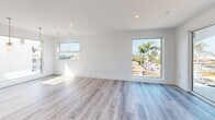 Located at 105-112 Avenida Mateo in the coastal community of San Clemente, California, this modern single-story home offers a thoughtfully designed layout with 3 bedrooms, 4 bathrooms, and an expansive floor plan that provides a true sense of openness and comfort. The interior is finished with light wood-tone flooring throughout, crisp white walls, and recessed lighting that enhances the bright, airy atmosphere across every room. The main living area is notably spacious, featuring large floor-to-ceiling sliding glass doors and multiple windows that frame views of the surrounding neighborhood's palm-lined streets, flooding the space with natural light. Elegant pendant lighting adds a refined touch overhead. The home includes two full kitchens, each showcasing contemporary design. The primary kitchen is a standout, equipped with a large center island with a gas cooktop, stainless steel appliances including a double oven and French door refrigerator, a sleek stainless range hood, and high-gloss white upper cabinetry paired with wood-toned lower cabinets. The bedrooms are well-proportioned and bright, with the primary suite offering walk-in closet space with built-in wire shelving systems. Large windows in the bedrooms capture neighborhood and palm tree views. With two closets, two hallways, and four full bathrooms, this home delivers practical functionality alongside its modern coastal aesthetic.