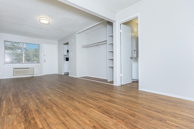 Enjoy a bright and open living space featuring sleek hardwood flooring and clean white walls. The high ceiling adds to the airy feel, creating the perfect canvas to make this space your own. - Casa Del Sol