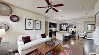 Located at 7145 Reading Rd in Rosenberg, TX, this single-story home offers a thoughtfully designed open-concept layout across two bedrooms and two bathrooms. The living room is bright and welcoming, featuring crown molding, a ceiling fan, and warm hardwood flooring that flows seamlessly into the adjoining dining and kitchen areas. The kitchen is a standout, showcasing dark espresso cabinetry reaching to the ceiling, granite countertops, stainless steel appliances, a central island with bar seating, and track lighting overhead. The dining area features additional track lighting and crown molding, creating an elegant setting for meals. The primary bedroom is generously sized with plush carpeting, natural light from large windows, and a ceiling fan. Its en-suite bathroom offers dark wood vanity cabinetry paired with granite countertops and a large mirror. A spacious walk-in closet with built-in shelving and hanging rods provides ample storage. The second bedroom is equally comfortable and well-lit. A hallway connects the living spaces efficiently. The attached garage provides secure parking and additional storage space, completing this well-rounded home.
