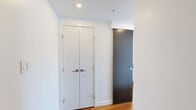 Located on a high floor at 655 Centre St S in Calgary, AB, this 2-bedroom, 1-bathroom unit offers a sleek, modern aesthetic defined by crisp white walls, warm hardwood flooring, and abundant natural light. The living room is a standout space, anchored by expansive floor-to-ceiling windows that frame breathtaking panoramic views of Calgary's downtown skyline and surrounding cityscape, flooding the interior with light throughout the day. The open, airy atmosphere makes this room ideal for both relaxing and entertaining.

The primary bedroom is a well-proportioned retreat featuring large windows with city views, a built-in open closet with shelving, a wall-mounted television, and a dedicated workspace with a desk — all finished in the same clean, minimalist style. The second bedroom mirrors this understated elegance, with its own closet and city-facing window. Both rooms are connected via a hallway with a distinctive dark sliding door that adds a bold design contrast to the otherwise bright interior.

The bathroom is finished to a high standard, showcasing marble-look tile flooring, a sleek floating vanity with an undermount sink, a large wall mirror, and a glass-enclosed shower. Throughout the unit, the consistent use of white tones, natural wood, and modern hardware creates a cohesive and sophisticated urban living environment.