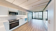 Located on the 14th floor of the 3zero3 building in Seattle's Belltown neighborhood, this thoughtfully designed residence delivers a clean, contemporary aesthetic throughout. Warm-toned hardwood flooring runs seamlessly across the open-plan layout, complementing the bright, paneled ceiling fitted with track lighting that adds both function and style.

The kitchen is a standout feature, outfitted with soft blue and white cabinetry, a marble-look backsplash, white quartz countertops, and stainless steel appliances including a GE range, built-in microwave, French door refrigerator, and a blue-accented dishwasher. Ample upper and lower cabinetry provides generous storage throughout.

The main living area is defined by expansive floor-to-ceiling windows and glass sliding doors that frame breathtaking views of Puget Sound and the surrounding Seattle cityscape, flooding the space with natural light. A frosted glass sliding partition offers flexible room division while maintaining the open, airy feel.

The bathroom is elegantly finished with large-format marble-look tile on both the floors and walls, a frameless glass walk-in shower, a floating white vanity with dual sinks, and backlit mirrors, creating a spa-like atmosphere. Every detail in this residence reflects a commitment to modern, high-quality urban living.