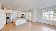 Located at 1 Hatcher Drive in Stockbridge, GA, this thoughtfully designed 2-bedroom, 2-bathroom residence offers a clean, contemporary aesthetic throughout its single-floor layout. The open-concept kitchen and living area serves as the heart of the home, anchored by a granite-topped center island illuminated by stylish pendant lights. White shaker cabinetry, a herringbone tile backsplash, stainless steel appliances, and light hardwood flooring complete the kitchen's modern appeal. The living area flows seamlessly from the kitchen and opens to a private balcony overlooking the surrounding community and mature tree line. Both bedrooms are carpeted for comfort, with large windows that invite natural light and offer outdoor views. The primary bedroom includes its own en-suite bathroom featuring a double granite-topped vanity, light tile flooring, and a tiled shower-tub combination. The second bathroom is equally well-finished with a full tub and shower surround. Each bedroom is accompanied by a dedicated closet outfitted with wire shelving systems for organized storage. Clean white walls, crisp trim work, and consistent finishes throughout give the space a bright, move-in ready feel.