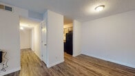 This single-floor 2-bedroom, 2-bathroom residence offers a practical and comfortable layout designed for everyday living. The open living area is a welcoming space, featuring rich wood-style laminate flooring and a large sliding glass door fitted with vertical blinds that fills the room with natural light and provides outdoor views. The textured ceilings are consistent throughout the main living spaces, adding a classic residential character.

The galley-style kitchen is efficiently designed with ample grey cabinetry, dark countertops, and a full suite of black appliances, including a refrigerator and electric range with overhead ventilation. A stainless steel sink and additional counter space make the kitchen highly functional. A utility panel is conveniently accessible from within the kitchen area.

The two bedrooms offer a quieter retreat, with plush carpeted flooring and windows dressed with horizontal blinds that allow for adjustable natural light. The bathrooms are equipped with a tub and shower combination, grey vanity cabinetry, and stone-tone countertops, providing a clean and cohesive aesthetic. Wood-style flooring extends into the bathrooms, tying the design together.

An entry hallway connects the main spaces smoothly, completing a well-organized floor plan suited for comfortable day-to-day living.