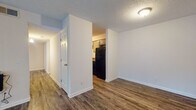 This single-floor 2-bedroom, 2-bathroom residence offers a practical and comfortable layout designed for everyday living. The open living area is a welcoming space, featuring rich wood-style laminate flooring and a large sliding glass door fitted with vertical blinds that fills the room with natural light and provides outdoor views. The textured ceilings are consistent throughout the main living spaces, adding a classic residential character.

The galley-style kitchen is efficiently designed with ample grey cabinetry, dark countertops, and a full suite of black appliances, including a refrigerator and electric range with overhead ventilation. A stainless steel sink and additional counter space make the kitchen highly functional. A utility panel is conveniently accessible from within the kitchen area.

The two bedrooms offer a quieter retreat, with plush carpeted flooring and windows dressed with horizontal blinds that allow for adjustable natural light. The bathrooms are equipped with a tub and shower combination, grey vanity cabinetry, and stone-tone countertops, providing a clean and cohesive aesthetic. Wood-style flooring extends into the bathrooms, tying the design together.

An entry hallway connects the main spaces smoothly, completing a well-organized floor plan suited for comfortable day-to-day living.