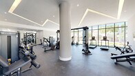 Located at 5961 SW 68th St in South Miami, FL, this professionally designed fitness center offers a generous, open-plan workout space across a single floor. The facility is characterized by its modern architectural design, featuring soaring ceilings with striking geometric recessed LED lighting that creates a bright, energizing atmosphere throughout.

Floor-to-ceiling glass windows line multiple walls, flooding the interior with abundant natural light and providing open views of the surrounding greenery and streetscape. The durable rubber-speckle flooring provides a practical and resilient surface suited to a full range of fitness activities.

A prominent central column adds a structural architectural element that naturally divides the space into distinct workout zones without enclosing them. The strength training area is well-equipped with a multi-station cable machine, selectorized weight machines, a free weight rack, and adjustable benches. The cardio zone features a row of Matrix-brand ellipticals, treadmills, and stationary bikes positioned to take full advantage of the natural light from the large windows.

A vibrant athletic-themed mural in bold teal and white anchors one wall, adding visual energy to the space. A dedicated area near the entrance accommodates stability balls and Smart Fitness equipment. Double glass doors provide easy access to an adjacent outdoor area. The overall ambiance is clean, contemporary, and motivating — purpose-built for an active lifestyle.