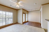 Located at 11900 Oakmoor Pkwy in Houston, TX, this one-bedroom, one-bathroom unit offers a well-planned single-floor layout designed for comfortable everyday living. The living room is a generously sized carpeted space featuring crown molding, a ceiling fan with light fixture, and track lighting along one wall. Large windows flood the room with natural light and offer outdoor views, while a wood-framed glass door provides access to a private entrance, adding both functionality and charm. The transition from carpet to wood-look flooring delineates the living and entry areas seamlessly. The kitchen is equipped with warm wood-toned cabinetry, a black refrigerator, and ample counter space, with a double-door closet nearby for added storage. The bedroom is a comfortable, carpeted retreat with its own ceiling fan, a large window with outdoor views, and direct access to a dedicated closet. The bathroom features a full tub-shower combination with white tile accented by a decorative gray tile border, warm wood cabinetry, and wood-look flooring. An in-unit laundry area adds everyday convenience. Throughout the space, warm neutral tones, crown molding, and consistent finishes create a cohesive and welcoming ambiance.
