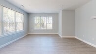 This well-appointed one-bedroom, one-bathroom unit in Swanzey, NH offers a thoughtfully designed single-floor layout with a clean, modern aesthetic. The open-concept kitchen and living area serves as the heart of the home, featuring crisp white cabinetry, a white subway tile backsplash, quartz countertops, and a suite of stainless steel appliances including a gas range, microwave, dishwasher, and refrigerator. A central kitchen island with a gray base provides additional prep space and casual seating. Pendant lighting adds a contemporary touch overhead, while light hardwood-style flooring flows seamlessly throughout the living areas. The living room is bright and airy, benefiting from multiple windows that invite natural light and offer views of the surrounding greenery. A glass door provides additional access and further enhances the sense of openness. The bedroom is a comfortable, well-sized retreat with its own window and the same light flooring, offering a calm and neutral environment. The bathroom features elegant marble-style tile flooring, a warm wood-toned vanity with ample drawer storage, and a clean, minimalist design with soft gray walls. The overall palette of soft grays, whites, and natural wood tones gives this unit a fresh, contemporary feel throughout.