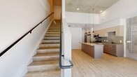 Located in Millcreek, Utah, this two-story, two-bedroom, two-bathroom residence blends contemporary design with industrial character across two well-appointed floors. The main level offers an open-concept layout anchored by a sleek kitchen featuring light wood cabinetry, stainless steel appliances including a gas range and French door refrigerator, quartz countertops, and a peninsula island illuminated by modern pendant lighting. Striking exposed concrete accent walls appear throughout the home, providing an urban industrial contrast against the crisp white walls and warm light wood flooring that run continuously through both levels. Floor-to-ceiling windows and a glass entry door flood the main living area with abundant natural light while framing views of the surrounding Millcreek neighborhood. A staircase connects to the upper floor, where the generously sized primary bedroom and second bedroom are located, each benefiting from natural light and the signature exposed concrete detailing. The two bathrooms are finished in a clean, modern style — one featuring a soaking tub with shower combination and matte black fixtures, and the other offering an illuminated vanity mirror with an undermount sink and contemporary cabinetry. Light wood flooring, high ceilings, and thoughtful finishes throughout give this residence a cohesive, modern aesthetic.