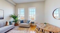 Located on Mason Street in Fall River, MA, this well-appointed 3-bedroom, 1-bathroom unit offers a thoughtfully designed single-floor layout. The living room is a standout space, featuring tall ceilings, warm hardwood floors, and a pair of large gridded windows that flood the room with natural light and frame views of the surrounding neighborhood. A mini-split system ensures year-round comfort. The galley-style kitchen is outfitted with white shaker cabinets, granite countertops, stainless steel appliances including a dishwasher, range, and built-in microwave, and a deep stainless sink — combining style with functionality. The three bedrooms are comfortably scaled with hardwood floors and high ceilings; the bedrooms include closets with bifold doors for convenient storage. The full bathroom features a tub-shower combination with sliding glass doors, a white vanity, and neutral tile flooring. A dedicated laundry area with a stacked washer and dryer adds everyday convenience. Two hallways connect the spaces efficiently throughout the unit. The overall aesthetic is clean and modern, with a neutral palette and consistent hardwood flooring creating a cohesive and inviting atmosphere throughout.
