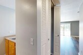 This efficiently designed single-floor unit offers a well-organized layout that makes smart use of its intimate footprint. The combined kitchen and living area forms the heart of the space, where rich hardwood-style plank flooring flows throughout and provides a warm, cohesive aesthetic. The living area is bright and open, benefiting from generous natural light that pours in through large sliding glass doors. These doors open to an outdoor view and are complemented by vertical blinds for privacy. A wall-mounted mini-split air conditioning unit and a baseboard heating system provide year-round climate control.

The kitchen is positioned at one end of the main living space, separated by a half-wall peninsula counter that doubles as a breakfast bar. Warm honey-toned wood cabinetry lines the upper and lower walls, offering ample storage, and is paired with white appliances including a refrigerator and a range. A dedicated overhead range hood and recessed lighting keep the kitchen functional and well-lit.

The bathroom features a wood-toned vanity with a white countertop sink, a well-lit mirror with a multi-bulb vanity light fixture, and hardwood-style flooring that ties in with the rest of the unit. A louvered bi-fold closet door in the hallway provides convenient storage access, rounding out this practical and well-appointed space.