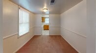 This two-floor residence is designed with a straightforward, functional layout spread across multiple rooms. The interior follows a consistent neutral color scheme, with white walls and warm beige carpeting throughout the bedroom areas, creating a clean and adaptable living environment.

The bedrooms are well-proportioned spaces, each finished with soft carpeting and white walls. Several rooms benefit from natural light provided by windows fitted with horizontal blinds. Ceiling fans with integrated light fixtures are present in multiple bedrooms, contributing to both comfort and ambient lighting. Floor vents indicate a central HVAC system serving the space.

The kitchen features warm oak cabinetry paired with light countertops and a stainless steel sink positioned beneath a window that allows natural light in. A dishwasher is included among the kitchen appliances. An adjacent carpeted dining or living area connects directly to the kitchen, offering a practical flow between spaces.

The bathrooms are finished with tile flooring in a neutral stone-like pattern. One bathroom includes a full tub-shower combination with white tile surround, a chrome shower rod, and a vanity with storage. A second, more compact bathroom provides essential fixtures in a clean, minimal layout.

Overall, the space presents a tidy, move-in-ready environment with consistent finishes throughout both floors.