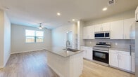 Located in Spring, TX, this thoughtfully designed single-story home offers 2 bedrooms, 3 bathrooms, and a functional open-concept layout. Light wood-style flooring flows consistently throughout the home, creating a cohesive and airy feel.

The kitchen serves as the centerpiece of the living area, featuring a large island with a granite countertop and undermount sink, crisp white cabinetry extending to the ceiling, a subway tile backsplash, and a full suite of stainless steel appliances including a side-by-side refrigerator, electric range, and microwave. Recessed lighting and built-in shelving add both practicality and style.

The open living area adjoins the kitchen seamlessly, brightened by a large window and a ceiling fan overhead. Both bedrooms are well-proportioned, each featuring ceiling fans, large windows with exterior views, and light-filled interiors. The spacious primary bedroom includes a walk-in closet outfitted with wire shelving for organized storage.

The bathrooms are finished with granite-topped vanities and marble-look tile surrounding the soaking tub and shower. Additional highlights include an in-unit laundry area. Clean neutral tones, modern hardware, and consistent finishes throughout give this home a polished, move-in-ready appeal.