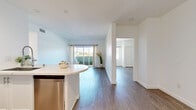 Located at 3400 Cahuenga Blvd W in Los Angeles, this well-appointed 2-bedroom, 2-bathroom residence offers a bright and modern living experience across a single floor. Light wood-style flooring flows seamlessly throughout, creating a clean and cohesive aesthetic.

The open kitchen and living area serves as the heart of the home. The kitchen is outfitted with crisp white shaker cabinetry reaching to the ceiling, stainless steel appliances including a refrigerator, range, and microwave, and a curved island with a white quartz countertop and a modern sink — ideal for both meal prep and casual dining. Recessed lighting illuminates the space, which opens to a spacious living area with sliding glass doors leading to a private balcony overlooking lush greenery.

Both bedrooms are generously sized, featuring large windows that invite natural light and offer views of the surrounding landscape. The primary bedroom includes a dedicated closet. Each room maintains the consistent light-toned flooring and clean white walls.

The two bathrooms offer distinct finishes: one features elegant marble mosaic tile flooring and a floating vanity with dual mirrors, while the second includes a glass-enclosed walk-in shower, wood-look flooring, and a sleek single vanity with a large mirror. A hallway connects all rooms efficiently, completing this well-designed residence.