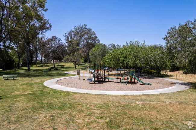 A view of the playground and picnic table amongst large trees at Hollywood Neighborhood Park