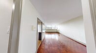 Located on the 7th floor at 30 Esterbrooke Ave in Toronto's North York neighbourhood, this 2-bedroom, 1-bathroom unit offers a well-organized layout across a single floor. Warm, richly toned parquet flooring flows throughout the living spaces and bedrooms, adding a classic character to the interior.

The combined kitchen and living room serves as the heart of the unit. The kitchen features dark cabinetry with granite-style countertops, a central island with additional counter space, stainless steel appliances including a refrigerator and stove, and tile flooring. The living area is bathed in natural light through expansive floor-to-ceiling windows, with a sliding door providing access to the balcony and sweeping views of the surrounding Toronto cityscape.

Both bedrooms continue the parquet flooring and are well-sized, with large windows that bring in natural light and city views. The primary bedroom offers generous space and access to a closet. A second closet provides additional storage within the unit.

The bathroom is clean and functional, featuring a full soaker tub and shower combination with white subway tile surround and brushed nickel fixtures. A hallway connects the rooms, completing the efficient and practical floor plan of this urban Toronto residence.
