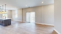 This well-appointed 2-bedroom, 3-bathroom residence at 298 W Monroe St in Dundee, Michigan offers a thoughtfully designed single-floor layout. Light-toned luxury vinyl plank flooring runs throughout, complementing the neutral warm-gray walls and clean white trim that give the space a cohesive, modern feel.

The open-concept kitchen is a standout feature, centered around a large island with an undermount sink, pendant lighting, and crisp white countertops. Dark wood-toned cabinetry extends floor to ceiling, providing ample storage, while a full suite of stainless steel appliances — including a French door refrigerator, electric range, and built-in microwave — adds a polished, contemporary touch. Natural light pours in through multiple windows overlooking the surroundings.

The spacious living room opens directly to a private balcony through sliding glass doors fitted with vertical blinds, offering pleasant outdoor views and additional natural light. Both bedrooms are generously sized with large windows and recessed lighting. The primary bedroom includes access to a dedicated closet. 

The three bathrooms are cleanly finished — one features a walk-in shower with a sleek black-framed glass enclosure, while another includes a full soaking tub/shower combination with built-in shelving and matte black fixtures.