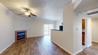 This single-story home is designed with a practical, open layout that connects the main living areas seamlessly. The living room is a standout space, featuring rich wood-look flooring, crown molding, a textured ceiling, and a ceiling fan with light. A corner fireplace with a tile surround serves as a focal point, adding warmth and character to the room. A sliding glass door fitted with vertical blinds invites natural light and provides access to the outdoors.

Adjacent to the living room, the kitchen is separated by a peninsula counter with a dark countertop, offering a natural transition between spaces. The kitchen is equipped with warm wood cabinetry, black appliances including a refrigerator and range, and light tile flooring. Recessed lighting and crown molding carry throughout, maintaining a consistent finish.

The bedrooms feature plush carpet, ceiling fans, and generous closet space, including a walk-in closet with wire shelving and a mirrored sliding-door closet. The bathrooms include wood-look flooring, warm wood vanity cabinetry, and a tub-shower combination. Built-in wire shelving near one bathroom provides additional storage. Overall, the home offers a clean, well-maintained interior with functional design throughout.