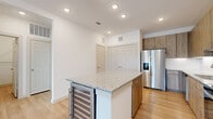 This well-appointed 2-bedroom, 2-bathroom single-floor residence offers a thoughtfully designed layout that balances comfort and modern style. The open-concept kitchen and living area serves as the heart of the home, featuring light wood-tone cabinetry, granite countertops, a subway tile backsplash, and a full suite of stainless steel appliances including a French door refrigerator with ice maker, electric range, microwave, and dishwasher. A central kitchen island with additional granite countertop space and a built-in wine cooler adds both functionality and character. Recessed lighting illuminates the kitchen and living areas, which flow seamlessly across light hardwood flooring. The living room benefits from a private exterior door with sidelight window, allowing natural light to fill the space, and is equipped with a ceiling fan. Both bedrooms are carpeted and feature ceiling fans; the generously sized primary bedroom includes access to a dedicated closet and connects to its own bathroom. Each bathroom is finished with granite-topped wood vanities, marble-surround tub/shower combinations or walk-in showers, and wood-look tile flooring. Two closets and a hallway complete this efficiently organized, contemporary residence.