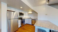 Located at 123 W Union St in Athens, Ohio, this multi-story property spans three floors and offers a thoughtfully designed layout with a blend of modern updates and functional living spaces. The kitchen is a standout feature, equipped with stainless steel appliances including a refrigerator, electric range, microwave, and dishwasher, all complemented by white cabinetry and light granite countertops. Warm hardwood-style flooring runs throughout the kitchen and living areas, adding a cohesive, inviting feel. The open living area is generously sized, bathed in natural light through multiple windows that frame views of the surrounding neighborhood's greenery. Track lighting accents the space, while a textured ceiling adds visual character. Bedrooms are finished with plush carpeting and include closets with built-in hanging rods, offering practical storage. The bathrooms feature white vanities with marble-patterned countertops, mirrored medicine cabinets, and brushed nickel hardware, maintaining a clean and modern aesthetic. A carpeted staircase connects the floors, with bright, airy stairwells that enhance the sense of openness. The multi-level layout of this Athens property provides distinct zones for living, sleeping, and everyday function.
