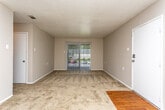 Located at 1449 Richland Rd in Auburn, Alabama, this single-floor unit offers a practical and comfortable layout across several well-defined living spaces. The entry opens into a generously sized living area finished with wall-to-wall carpeting, neutral-toned walls, and a textured ceiling. A sliding glass door fitted with vertical blinds allows natural light to fill the room and provides outdoor access. The living space flows conveniently toward a central hallway that connects the remaining rooms. The galley-style kitchen features warm wood cabinetry, ample upper and lower storage, a double-basin sink, a black electric range, and a full-size refrigerator, all set atop easy-to-maintain hardwood-style flooring. The bedrooms are carpeted and offer a calm, neutral palette, with windows dressed in blinds that bring in soft natural light. At least one bedroom includes a reach-in closet with a rod and shelving for organized storage. The bathroom is well-appointed with a single-sink vanity, hardwood-style flooring, and a full tub and shower combination surrounded by clean white tile. A second full bathroom features an all-white tiled tub and shower enclosure. Throughout the unit, the consistent neutral finishes and functional design create a clean and move-in-ready environment.