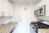 Located at 2000 N Adams St in Arlington, VA, this 2-bedroom, 1-bathroom unit offers a well-organized single-floor layout designed for comfortable everyday living. The living room greets you with light wood-look flooring, neutral white walls, and large windows fitted with blinds that allow natural light to stream in and cast warm patterns across the floor, creating a bright and airy atmosphere.

The galley-style kitchen is thoughtfully appointed with white cabinetry, granite countertops, light wood-look flooring, and a suite of stainless steel appliances including a gas range, built-in microwave, and dishwasher — making it both functional and stylish.

Both bedrooms are carpeted and feature ceiling fans with light fixtures, providing comfort year-round. Each room is served by closets with double-panel doors for ample storage. The primary bedroom is generously sized and receives natural light through a large window with a pleasant outdoor view. The second bedroom mirrors a similar layout, maintaining a cohesive feel throughout.

The bathroom is clean and straightforward, featuring a full tub-shower combination with white tile surround. The overall aesthetic of the unit is clean, neutral, and move-in ready, offering a comfortable living environment in a well-located Arlington address.