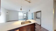 Located in Chicago's vibrant North Halsted neighborhood, this two-bedroom, three-bathroom residence offers a well-designed layout with modern finishes and breathtaking city skyline views. Rich hardwood flooring flows throughout the main living areas, complementing the clean, contemporary aesthetic.

The open-concept kitchen serves as the heart of the home, featuring dark espresso cabinetry, stainless steel appliances, a spacious peninsula with a light quartz countertop and undermount sink, and pendant lighting overhead. A stacked in-unit washer and dryer add everyday convenience. The kitchen connects seamlessly to the living area, which is bathed in natural light from expansive floor-to-ceiling windows and provides direct access to a private balcony showcasing panoramic views of the Chicago skyline.

The primary bedroom is generously sized, offering balcony access and large windows that frame the cityscape. It is accompanied by a walk-in closet with built-in shelving. The en-suite primary bathroom features a dual-sink vanity with dark wood cabinetry, a large mirror, and a tiled shower. Two additional bathrooms serve the second bedroom and guests. Three closets throughout the residence provide ample storage. The overall ambiance is bright, modern, and urban.