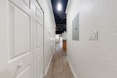 Located at 100 Seabreeze Blvd in Daytona Beach, Florida, this one-bedroom, three-bathroom residence offers a distinctive industrial-inspired aesthetic across a single thoughtfully laid-out floor. Light wood-look luxury vinyl flooring runs throughout, complemented by crisp white walls and clean white baseboards that create a bright, cohesive feel.

The unit is entered through a dedicated entrance and features a long corridor with pendant lighting and an exposed black ceiling, lending a loft-like character to the space. The main living area continues this bold design with soaring ceilings that reveal industrial ductwork and structural elements, adding visual interest and height.

The kitchen is well-appointed with warm honey-toned wood cabinetry, dark granite-style countertops, and stainless steel appliances including a range and over-the-range microwave. The primary bedroom is a comfortable, sunlit space featuring a window with exterior views and direct access to generous closet storage — three closets in total, including a walk-in with wire shelving systems.

The bathrooms include a standout tiled shower with large-format stone-look tiles, mosaic tile flooring, and matte black fixtures. A dedicated laundry room houses a full-size washer and dryer with overhead shelving. The unit's combination of functional layout and industrial character makes it a distinctive offering in Daytona Beach.