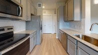 This single-floor residence offers a thoughtfully designed layout with modern finishes throughout. The galley-style kitchen is a standout feature, showcasing gray shaker cabinets, granite countertops, a subway tile backsplash, and a full suite of stainless steel appliances including an electric range, refrigerator, dishwasher, and built-in microwave. Light wood-style flooring runs throughout the main living areas, lending warmth and cohesion to the space.

The open living area is bright and welcoming, benefiting from multiple windows that invite natural light and offer views of the surrounding greenery. A pendant light fixture and ceiling fans add functional detail to the living spaces.

The bedrooms are carpeted for comfort and each features closet storage, with at least one offering a walk-in style closet. The rooms are neutral in tone, with large windows providing natural light and outdoor views.

Two bathrooms mirror the kitchen's design language, featuring gray cabinetry, granite-topped vanities, and large framed mirrors. One bathroom includes a shower-tub combination, while the other offers a similar tub-shower setup with overhead cabinetry for added storage.

Overall, the space presents a clean, contemporary aesthetic with consistent finishes, making it a functional and visually cohesive home.