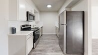 This two-story, 3-bedroom, 4-bathroom home in Tulsa, Oklahoma offers a well-organized layout spread evenly across two floors. The main level sets a clean, contemporary tone with wood-look vinyl plank flooring throughout the common areas and a textured ceiling finish. The galley-style kitchen is a standout feature, showcasing white shaker cabinetry, white subway tile backsplash, light countertops, and a full suite of stainless steel appliances including a refrigerator, range, microwave, and dishwasher. A dedicated in-unit laundry room adds everyday convenience. The upper floor hosts the generously sized primary bedroom, a spacious retreat with its own closet and bathroom featuring a soaking tub/shower combo. The additional bedrooms are carpeted and equipped with ceiling fans and closets, offering comfortable, functional spaces. All four bathrooms maintain a consistent, clean aesthetic with white tiled tub surrounds and neutral finishes. A hallway connects the upper-level rooms efficiently. A balcony provides outdoor access with views of the surrounding community grounds. Throughout, the neutral color palette, updated flooring, and modern fixtures create a cohesive and move-in-ready atmosphere.