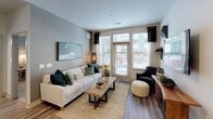 This well-appointed single-floor residence offers a thoughtfully designed open-concept layout that seamlessly connects the kitchen, dining, and living areas. The kitchen is a standout feature, showcasing dark espresso cabinetry, granite countertops, a tile backsplash, stainless steel appliances including a refrigerator, dishwasher, and microwave, and a large center island with an electric cooktop that doubles as a breakfast bar with seating. Pendant lighting above the island adds a refined touch. The living room is bright and welcoming, with large windows and a glass door that invite ample natural light and offer outdoor views. Wood-style flooring runs throughout the main living areas, adding warmth and continuity. Two spacious bedrooms feature plush carpet, generous windows, and ceiling fans. The primary bedroom includes an en-suite bathroom with a dual-sink granite vanity, LED-backlit mirror, glass-enclosed shower, and direct access to a walk-in closet. A second bathroom mirrors the same high-quality finishes, also connecting to a walk-in closet. The overall aesthetic is modern and cohesive, with neutral tones and clean architectural lines throughout.