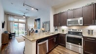 Located at 770 N Eldridge Pkwy in Houston's Energy Corridor, this thoughtfully designed one-bedroom, two-bathroom residence offers a well-appointed single-floor layout that maximizes every inch of its compact footprint. Rich wood-look flooring flows throughout the main living areas, anchoring a cohesive and modern aesthetic.

The open-concept kitchen is a standout feature, showcasing dark espresso cabinetry extending to near the ceiling, granite countertops, a tile backsplash, and a full suite of stainless steel appliances including a refrigerator, range, microwave, and dishwasher. A peninsula with bar seating creates a natural transition into the living area, ideal for casual dining or entertaining.

The living room is bright and inviting, with a ceiling fan, hardwood-style flooring, and a sliding glass door that opens to a private outdoor space with views of the community amenities, allowing for an abundance of natural light.

The primary bedroom is a comfortable retreat, carpeted for warmth, with large windows, patterned drapes, and access to a spacious walk-in closet with multi-tiered hanging storage. The room accommodates a king-sized bed with ease.

Two full bathrooms serve the residence, providing convenience for both residents and guests. Track lighting and recessed fixtures throughout ensure well-lit interiors across the entire space.