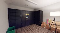 Located at 150 Chateau Terr in Athens, Georgia, this dedicated package locker room provides a practical and well-organized solution for secure parcel management. The single-floor space is outfitted with multiple Luxer One smart locker systems, featuring a large bank of individually numbered black locker compartments that accommodate packages of varying sizes. A centrally positioned interactive touchscreen kiosk allows residents to receive notifications and retrieve their deliveries with ease. An additional standalone Luxer One tower locker unit offers capacity for oversized packages that cannot fit within the standard compartments. The room features wood-look plank flooring and neutral gray walls, creating a clean, no-frills environment designed for functionality. Overhead fluorescent lighting ensures the space is well-illuminated for easy navigation. A standard interior door provides access to the room, and a recycling bin is conveniently available near the entrance. The layout is straightforward and efficient, maximizing the available floor space to accommodate both the locker systems and any overflow packages awaiting pickup. Overall, this package locker room delivers a streamlined, secure, and accessible amenity for residents at this Athens community.