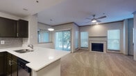 Located at 2811 La Frontera Blvd in Round Rock, Texas, this single-floor residence offers a thoughtfully designed layout with modern finishes throughout. The open-concept kitchen and living area serves as the heart of the home, where wood-look flooring, dark espresso cabinetry, and a gray subway tile backsplash complement stainless steel appliances. A peninsula with a white quartz countertop provides additional prep space and connects seamlessly to the living area. Pendant lighting and a flush-mount ceiling fixture illuminate the kitchen, while a large sliding glass door floods the living room with natural light and provides access to an outdoor area. A ceiling fan and a tile-surround fireplace add both comfort and character to the living space. Crown molding and neutral-toned walls contribute to the clean, cohesive aesthetic throughout. The bedrooms are carpeted and generously sized, each featuring ceiling fans and ample natural light from blinds-covered windows. One bedroom includes built-in shelving and a dedicated desk nook, ideal as a home office. The primary bathroom offers dual vanities with dark cabinetry, quartz countertops, a walk-in shower, and wood-look flooring. A dedicated laundry closet with a full-size washer and dryer adds everyday convenience.