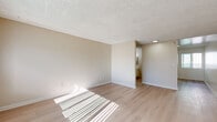 Located at 13707 Doty Ave in Hawthorne, California, this efficiently designed single-floor unit offers a thoughtful layout across a cozy footprint. Light wood-look flooring runs continuously throughout the space, creating a cohesive and clean aesthetic that enhances the sense of openness.

The living room is a bright, airy space bathed in natural light streaming through vertical-blind-covered windows. Warm beige walls and a textured popcorn ceiling give the room a comfortable, neutral character, while a wall-mounted heating unit adds practical functionality.

The kitchen is well-appointed with crisp white cabinetry — both upper and lower — fitted with black hardware for a modern contrast. A double stainless steel sink with a sleek black faucet, light speckled countertops, and a stainless steel electric range with an overhead ventilation hood make this a fully functional cooking space. A window allows natural light to fill the kitchen area.

The unit includes two bathrooms, one of which features a clean white tub-shower combination with chrome fixtures and a black showerhead. A dedicated closet provides additional storage to maximize the unit's utility.

Overall, the space presents a clean, move-in-ready environment with a bright, minimalist palette that feels open and welcoming throughout.