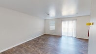 Located on Cabin Creek Court in Hopewell, Virginia, this single-story home offers a clean, neutral interior designed for comfortable everyday living. The open layout is evident from the 3D floor plan, which reveals a well-organized arrangement of living, kitchen, and bedroom spaces.

The living area is spacious and bright, finished with durable wood-look flooring that runs throughout the main areas of the home. Large vertical blinds frame a sliding glass door that allows abundant natural light and provides outdoor access, while an additional window further enhances the airy feel of the room.

The kitchen is well-equipped with white cabinetry, dark countertops, and a full suite of appliances including a stainless steel range, dishwasher, and refrigerator. A double-basin sink sits beneath a window, adding natural light to the workspace.

The bedrooms feature soft, wall-to-wall carpeting and are illuminated by natural light from multiple windows fitted with blinds. Each room offers a calm, neutral palette suitable for a variety of uses.

The bathroom includes a full tub-shower combination with clean white surroundings and wood-look flooring, maintaining a consistent aesthetic throughout the home.
