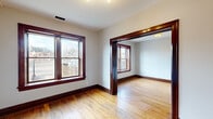 This single-floor unit offers a practical and thoughtfully designed layout comprising two bedrooms, two bathrooms, a kitchen, dining room, and hallway. Throughout the living areas and bedrooms, warm hardwood floors are paired with rich, dark-stained wood trim, baseboards, and door frames, creating a classic aesthetic that ties the space together cohesively.

The kitchen is a standout feature, equipped with stainless steel appliances, white shaker cabinetry, a subway tile backsplash, and a granite-topped peninsula that provides additional prep and dining space. Natural light enters through a window above the sink area.

The two bedrooms are modestly sized with hardwood floors and dark wood trim consistent with the rest of the unit. The primary bedroom benefits from a large double-pane window with exterior views, while the second bedroom offers a quieter, more compact layout.

Both bathrooms are notably well-appointed, featuring white subway tile walk-in showers with sliding glass doors framed in brushed gold hardware, a classic pedestal sink, an octagon-and-dot tile floor with green accent tiles, sage green wainscoting, and a gold-framed mirror — lending a boutique, design-forward character to the space.