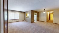 Located at 6001 Marine Pkwy in Mentor-on-the-Lake, Ohio, this single-floor unit offers a straightforward, functional layout designed for comfortable everyday living. The open living and dining area is generously sized, finished with neutral wall-to-wall carpeting and a textured ceiling. A large window fitted with vertical blinds allows natural light to fill the space, while a pendant light fixture serves as a focal point over the dining area. A centrally positioned accent wall houses a pass-through window that connects the main living space to the kitchen, enhancing the open feel of the floor plan.

The kitchen is well-equipped with warm wood-toned cabinetry extending to the upper and lower walls, providing ample storage. Light countertops, a single-basin sink, a gas range, and a refrigerator complete the space, which is finished with neutral tile flooring. A window above the sink brings in additional natural light.

Two carpeted bedrooms each feature wide bifold closet doors that open to full-width closet spaces with hanging rods, offering practical storage. The full bathroom includes a tiled floor, a vanity with wood cabinetry, a toilet, and a tub-shower combination. A hallway connects the bedroom wing to the main living areas, creating a cohesive and efficient flow throughout the unit.