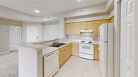 Located in Coconut Creek, FL, this well-appointed 2-bedroom, 2-bathroom residence offers a thoughtfully designed single-floor layout that maximizes comfort and functionality. The open-concept living and dining area is finished with neutral-toned carpet and bathed in natural light, flowing seamlessly toward a private balcony accessible via sliding glass doors. The balcony overlooks a sparkling pool, providing a relaxing outdoor retreat. The kitchen features light wood cabinetry, a peninsula with a double sink, white appliances including a range and refrigerator, and tile flooring—all connected to the living area via a convenient pass-through counter. A dedicated pantry and ample storage add to its practicality. The spacious primary bedroom includes multiple windows framing lush palm tree views, while the second bedroom also benefits from generous natural light and closet space. Both bathrooms are clean and functional, with one featuring a full tub-shower combination with white tile surround and a vanity with mirror. Additional conveniences include a dedicated laundry area, utility room, hallway, and four closets throughout the unit, ensuring plentiful storage. The overall aesthetic is light, neutral, and move-in ready.
