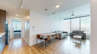 Located in Houston's vibrant Texas Medical Center area, this 4-bedroom, 4-bathroom residence offers a modern, efficiently designed layout with clean lines and a bright, open atmosphere. Light wood flooring runs throughout, complementing the crisp white walls and creating a warm, cohesive aesthetic.

The open-concept living, dining, and kitchen area serves as the heart of the home. The living room is anchored by floor-to-ceiling windows that frame sweeping panoramic views of the Houston skyline, flooding the space with abundant natural light. A ceiling fan adds a practical touch. The kitchen is well-appointed with rich wood cabinetry, stainless steel appliances including a range and built-in microwave, a tiled backsplash, and track lighting overhead.

Each of the four bedrooms features large floor-to-ceiling windows offering impressive city views, wood flooring, and dedicated closet space. The primary bedroom provides a more generous footprint among the four. The four bathrooms are finished with clean white subway-style tile surrounds in the tub-shower combinations, wood-toned cabinetry, and light flooring, maintaining the modern design language found throughout. A dedicated laundry area and multiple hallways complete this well-organized, high-rise residence.