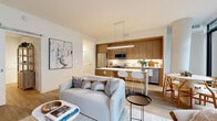 Located at 4909 Auburn Ave in the heart of Bethesda, MD, this thoughtfully designed 3-bedroom, 2-bathroom residence offers a contemporary open-concept layout across a single floor. The living and kitchen area forms the heart of the home, where warm wood cabinetry with full-height paneling, stainless steel appliances, and a white quartz peninsula with bar seating create a stylish and functional space. Light hardwood flooring flows throughout, complementing the clean white walls and modern finishes. The living area is bathed in natural light from dramatic floor-to-ceiling sliding glass doors that open directly onto a private balcony, offering views of the surrounding Bethesda streetscape. A built-in shelving nook adjacent to the dining area adds both character and practicality. The primary bedroom features direct balcony access and generous proportions, while the additional bedrooms are comfortably sized with soft neutral tones. Two well-appointed bathrooms serve the residence — one featuring marble-look tile surround with a soaking tub, and the other with a glass-enclosed shower and wood-toned vanity. Two closets provide ample storage. The overall ambiance is bright, clean, and modern, ideal for contemporary urban living.
