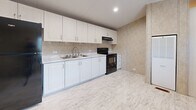 Located at 2214 E Fourth Ave in Hutchinson, Kansas, this single-story, two-bedroom, one-bathroom home offers a compact yet efficiently organized layout across its single floor. The elongated floor plan, visible in the 3D overview, arranges all rooms along a central corridor, maximizing usability throughout the space.

The kitchen is equipped with white shaker-style cabinetry extending from base to upper wall, light-toned countertops, a double-basin sink, a black electric range, and a refrigerator. Recessed lighting and light wood-look flooring contribute to a clean, functional cooking environment.

The primary bedroom is notably spacious, featuring vaulted ceilings, neutral textured wall panels, light wood-look flooring, and a window with blinds that admits natural light. An adjoining bathroom is directly accessible from this room. The second bedroom is similarly appointed with matching flooring, textured walls, vaulted ceilings, a window, and a wall-mounted clothing rod for storage.

The bathroom includes a full tub-shower combination with a handheld showerhead, tile-look wall surround, a toilet, and a vanity with white cabinetry. The hallway area features a built-in HVAC unit, providing centralized climate control. Consistent light flooring and neutral wall tones throughout create a cohesive, understated ambiance.