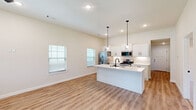 This single-story home offers a thoughtfully designed layout encompassing 2 bedrooms, 3 bathrooms, a garage, and a dedicated laundry room. The open-concept kitchen and living area serves as the heart of the home, featuring warm luxury vinyl plank flooring, vaulted ceilings, and abundant natural light from multiple windows with blinds. A ceiling fan adds both comfort and style to the living area, which also includes a front entry door with glass panel accents.

The kitchen is a standout space, showcasing white shaker-style cabinetry with matte black hardware, light quartz countertops, a white subway tile backsplash, and stainless steel appliances including a gas range, built-in microwave, and French door refrigerator. A large center island with a built-in sink and matte black faucet provides additional prep space and casual seating.

The bedrooms are carpeted for comfort, each equipped with ceiling fans and natural light. The spacious primary bedroom offers a generous footprint with ample room for furnishings. The bathrooms are finished in a clean, modern palette with white cabinetry, quartz counters, matte black fixtures, and tiled tub-shower combinations. The laundry room includes overhead cabinetry and LVP flooring, while the attached garage adds convenient storage and parking.