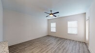 This single-story space is designed with a clean, modern aesthetic, combining functionality with a bright and airy atmosphere. The open-concept living area serves as the heart of the unit, featuring wood-look plank flooring that flows seamlessly throughout the main spaces. A ceiling fan with a built-in light fixture anchors the room, while multiple windows fitted with horizontal blinds allow natural light to fill the space, creating a welcoming ambiance.

The kitchen is well-equipped with stainless steel appliances, including a full-size refrigerator and range, complemented by white cabinetry, granite-style countertops, and a subway tile backsplash. Pendant lighting above the kitchen counter adds a polished finishing touch. The layout connects effortlessly to the main living area, making it ideal for everyday use.

The bedrooms offer a softer feel with plush carpeting, ceiling fans, and natural light from well-placed windows. Each room provides a calm, neutral environment. An adjacent bathroom features a tub-shower combination with marble-style tile surround, a white vanity with granite countertop, brushed nickel hardware, and wood-look flooring, completing the cohesive design found throughout the space.