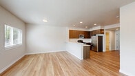 This 2-bedroom, 2-bathroom residence offers a thoughtfully designed single-floor layout with a clean, modern aesthetic throughout. The open-concept kitchen and living area serves as the heart of the home, featuring light hardwood-style flooring, recessed lighting, and a seamless flow between spaces. The kitchen is well-equipped with rich wood-toned cabinetry, light countertops, and a full suite of stainless steel appliances including a refrigerator, range, microwave, and dishwasher, centered around a peninsula that provides additional prep and casual dining space. The adjacent living area is bright and airy, with multiple windows allowing natural light to fill the room.

The primary bedroom is a comfortable retreat featuring a sliding glass door that opens to a private balcony overlooking a lush green yard and mature trees. The second bedroom offers plush carpeting, a sliding closet, and a window with natural views. Both bathrooms are finished with neutral tile flooring, clean white fixtures, and wood-toned vanity cabinetry. A hallway connects the rooms efficiently. The balcony provides an inviting outdoor space with an open view of the landscaped surroundings, completing this well-rounded and functional residence.