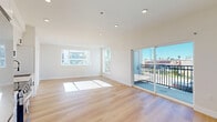 Located at 2301 Ulric Street in San Diego, CA, this thoughtfully designed 2-bedroom, 2-bathroom residence offers a bright and modern living experience. The open-concept kitchen and living area serves as the heart of the home, featuring light wood flooring throughout, recessed lighting, and large windows and sliding glass doors that flood the space with natural sunlight. The kitchen is outfitted with crisp white shaker cabinetry, a subway tile backsplash, stainless steel appliances including a French door refrigerator, gas range, built-in microwave, and dishwasher. Sliding doors lead directly to a private balcony with views of the surrounding neighborhood, including palm trees and the San Diego skyline. The spacious primary bedroom enjoys generous natural light through a large picture window and includes a wide sliding-door closet. The second bedroom is equally well-lit and comfortable. Both bathrooms feature clean, all-white finishes with modern matte black hardware, walk-in showers, and wood-look flooring. A hallway with a recessed electrical panel connects the living areas to the bedrooms, with additional closet storage throughout. The overall aesthetic is clean, contemporary, and move-in ready.