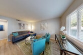 Located at 2052 Wilkins Ave in Napa, California, this thoughtfully designed one-bedroom, one-bathroom residence offers a comfortable and efficient single-floor layout. The open-concept living and kitchen area serves as the heart of the home, featuring light hardwood-style flooring, neutral gray walls, and natural light streaming through slatted blinds. The living room provides an inviting atmosphere with ample space for seating and a defined dining area. The kitchen is well-equipped with crisp white shaker-style cabinetry, stainless steel appliances including a full-size refrigerator and gas range, a light countertop peninsula with bar seating, and a ceiling fan overhead. The bedroom offers a comfortable retreat with plush carpeting, a spacious walk-in closet with full rod storage, and room for a queen-sized bed and additional furnishings. The bathroom features classic wainscoting, tile flooring, a white vanity with ample storage, and a shower-tub combination. Two closets throughout the unit provide generous storage. The space presents a clean, modern aesthetic with a warm and welcoming ambiance throughout.