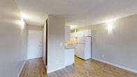 This single-floor, 2-bedroom, 1-bathroom unit offers a practical and well-organized layout. The living room is the largest shared space, featuring wood-style plank flooring, neutral-toned walls, and a textured ceiling. A sliding glass door at the far end fills the room with natural light and provides access to a private balcony with outdoor views, enhancing the sense of openness.

The galley-style kitchen runs along a narrow corridor and is efficiently designed with white upper and lower cabinetry, gray laminate countertops, a stainless single-basin sink, and white appliances including a range and full-size refrigerator. A window above the counter brings in additional natural light.

Both bedrooms feature carpet flooring, neutral walls, and windows with horizontal blinds overlooking greenery. The primary bedroom includes a sliding-door closet with a built-in shelf. A hallway connects the bedrooms to the shared full bathroom, which includes a tub-shower combination, a white vanity with gray countertop, and wood-style flooring consistent with the rest of the unit's common areas.